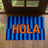 Palabra "HOLA" en naranja sobre fondo de rayas verticales azules y azul marino sutex rug 2x3 overhead lifestyle2