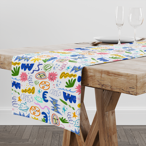 Coloridos dibujos doodle infantiles con formas abstractas, espirales, estrellas y líneas onduladas en azul, amarillo, rosa y verde. table runner mockup