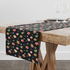 Patrón navideño con galletas decoradas en forma de estrellas, copos de nieve, árbol, casa y muñeco de jengibre sobre fondo negro. table runner mockup