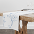 Patrón botánico de líneas azules que muestra flores y hojas en un estilo de dibujo minimalista sobre fondo blanco. table runner mockup