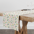 Patrón floral con rosas rosadas y amarillas sobre fondo de rayas beige y crema con hojas verdes table runner mockup