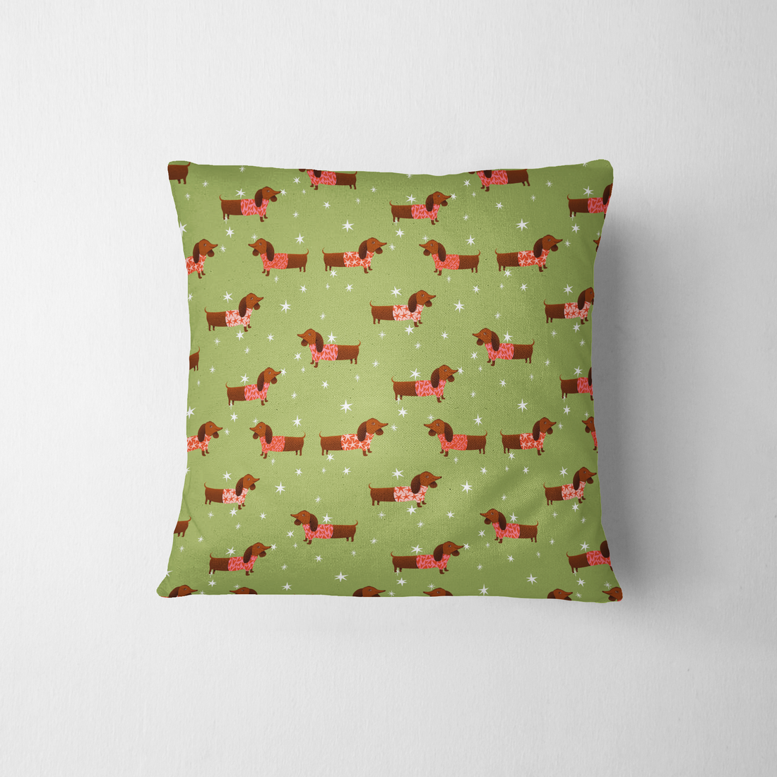 Patrón de perros salchichas marrones con bufandas rojas navideñas sobre fondo verde con estrellas blancas. fabric pillow mockup